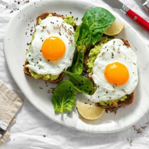 Top view healthy avocado toasts for breakfast or lunch with rye bread, avocado puree toast and fried eggs on white background