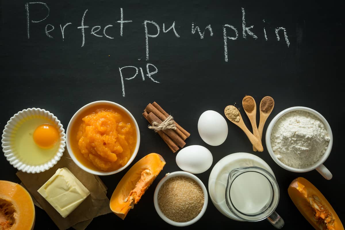 pumpkin pie ingredients in bowls on black background