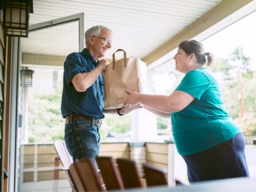 woman delivering a meal train meal to an elderly man
