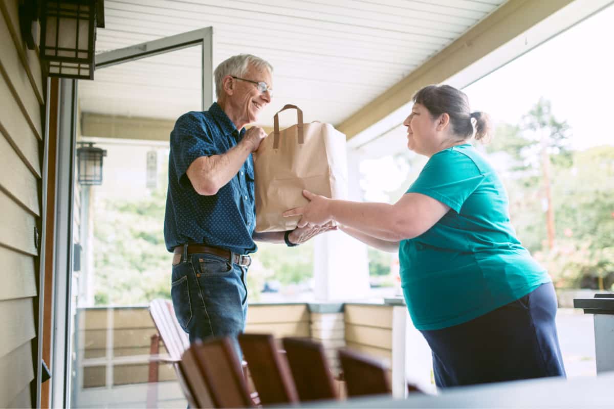 woman delivering a meal train meal to an elderly man