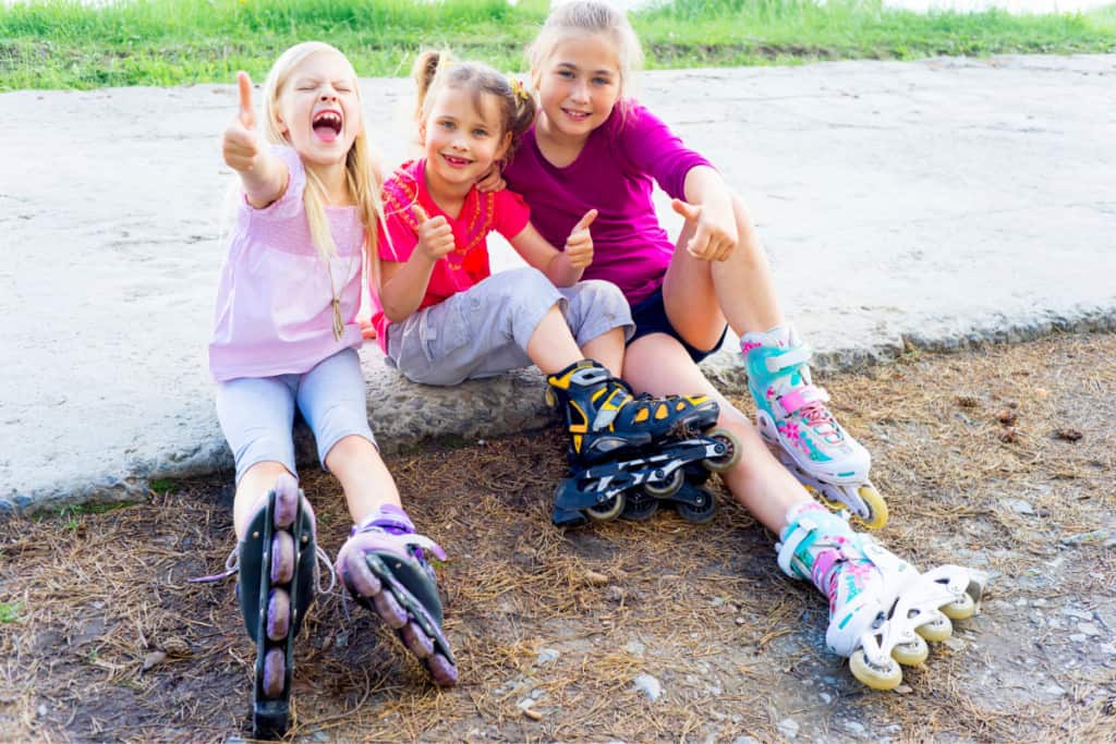 girls sitting on the ground wearing rollerblades