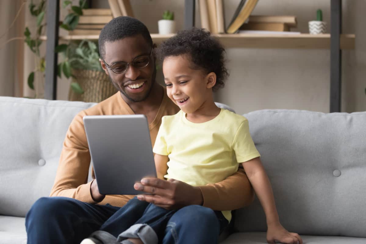 Father and son smiling at tablet
