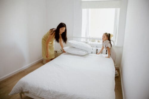 mom and daughter making the bed